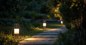 Moderne Sockelleuchten beleuchten einen Gartenweg in der Abenddämmerung